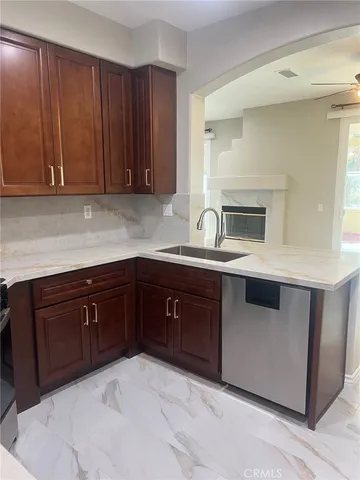 a kitchen with granite countertop a sink dishwasher stove and cabinets