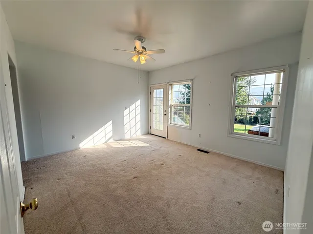 an empty room with windows and chandelier fan