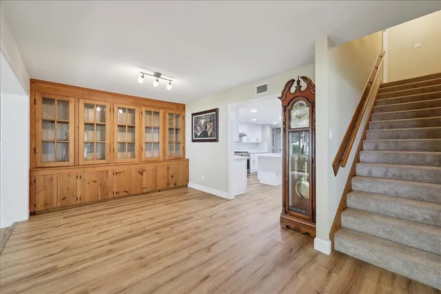a view of an empty room with wooden floor and stairs