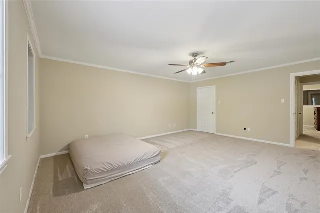 an empty room with a chandelier fan and windows