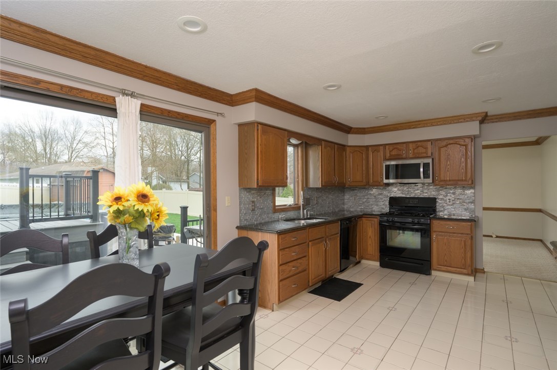 819 Bridge Road Akron, OH 44312 - Photo 17 of 33 Kitchen with black stove and dishwasher, dark granite countertops, striking backsplash and a large sink