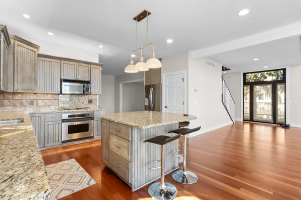 a kitchen with granite countertop a stove top oven a sink dishwasher a dining table and chairs with wooden floor