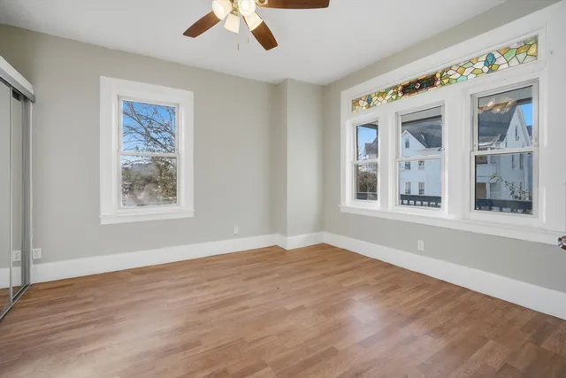 a view of an empty room with a window and wooden floor