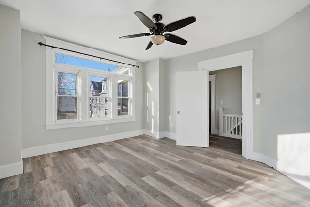 a view of empty room with wooden floor and ceiling fan
