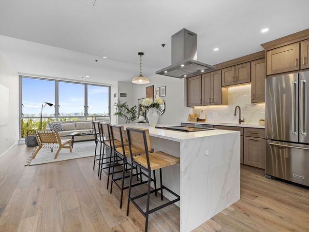 a kitchen with stainless steel appliances kitchen island granite countertop a refrigerator a stove a sink a dining table and chairs with wooden floor