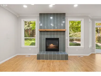 a view of an empty room with wooden floor and a fireplace