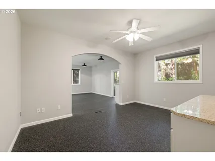 a view of an empty room with wooden floor and a ceiling fan