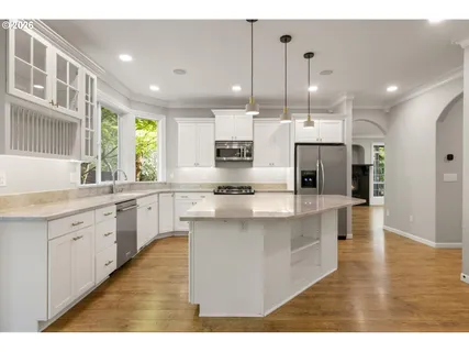 a large kitchen with kitchen island a sink a center island stainless steel appliances and a window