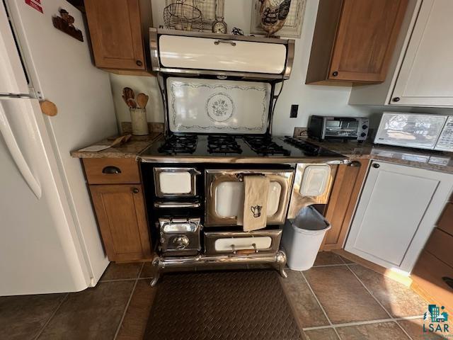 2734 Bear Island River Road Ely, MN 55731 - Photo 5 of 37 Kitchen featuring white appliances, brown cabinets, exhaust hood, dark tile patterned flooring, and dark stone countertops
