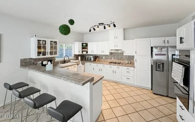 a dining area with stainless steel appliances kitchen island granite countertop a dining table chairs and a refrigerator