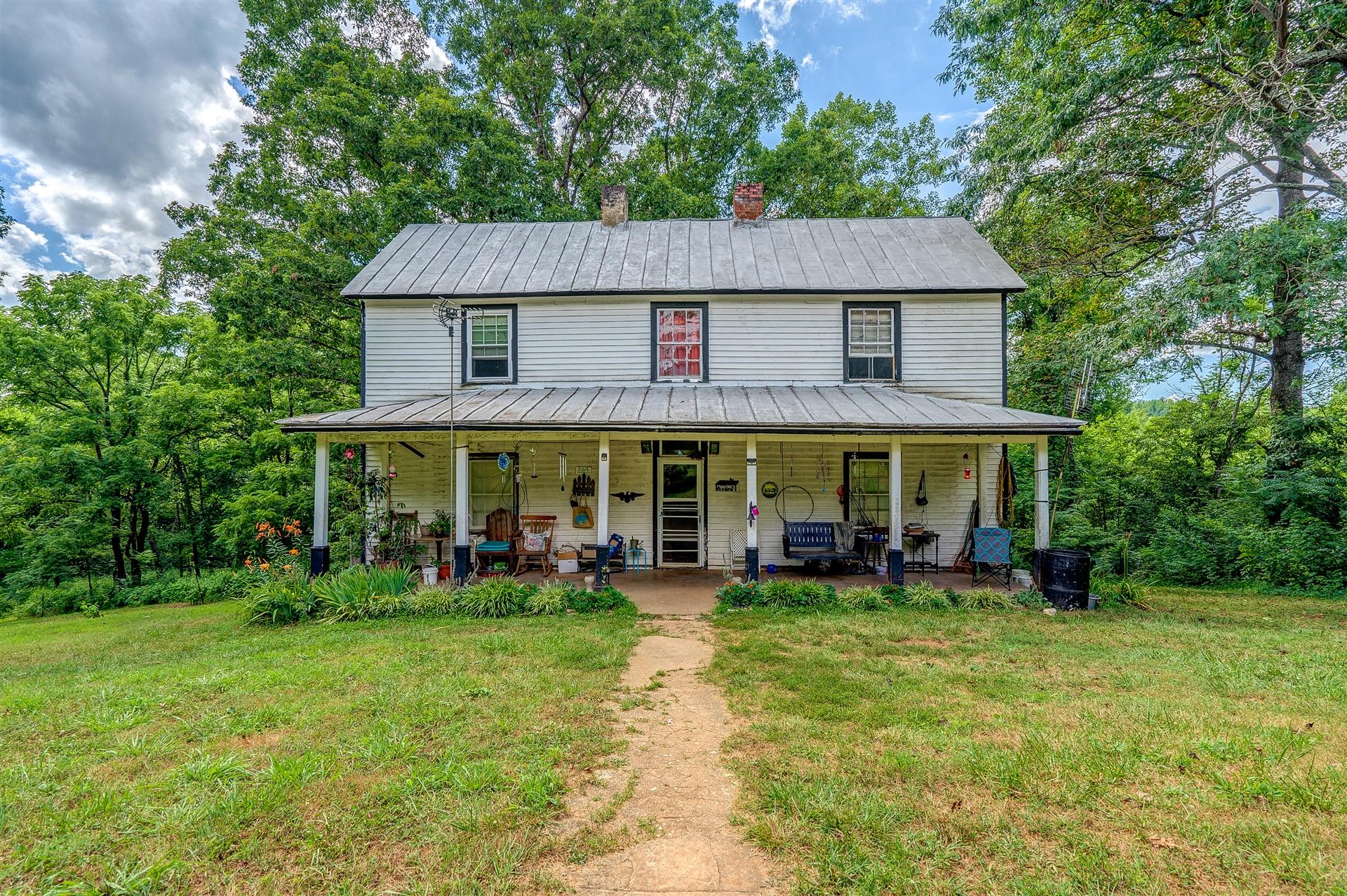6051 Ferrum Mountain Road Callaway, VA 24067 - Photo 7 of 14 a view of a white house with a yard table and chairs under an umbrella