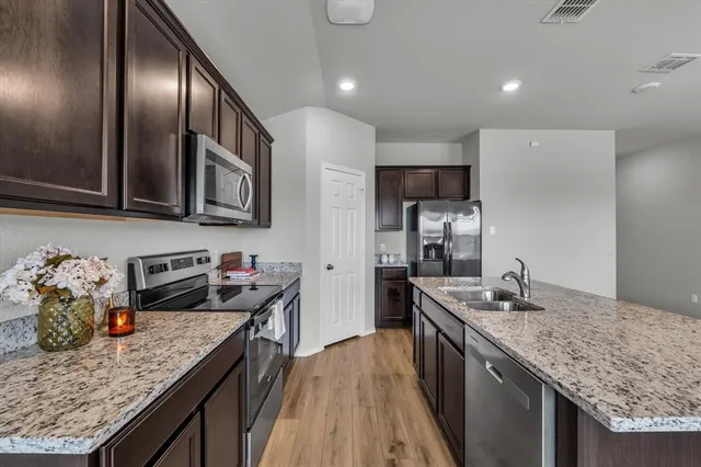 a kitchen with granite countertop stainless steel appliances a sink stove top oven and cabinets