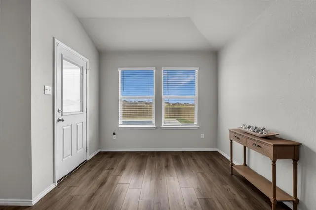 an empty room with wooden floor closet and windows