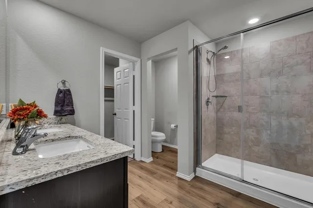 a bathroom with a granite countertop sink a toilet and shower