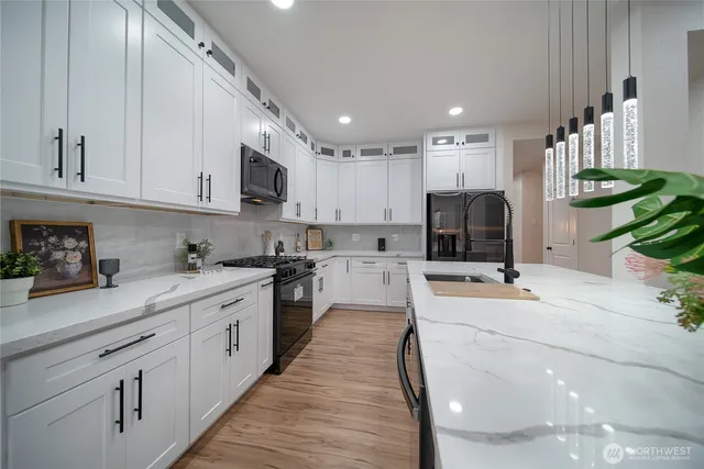 a large white kitchen with stainless steel appliances granite countertop a lot of counter space and a sink