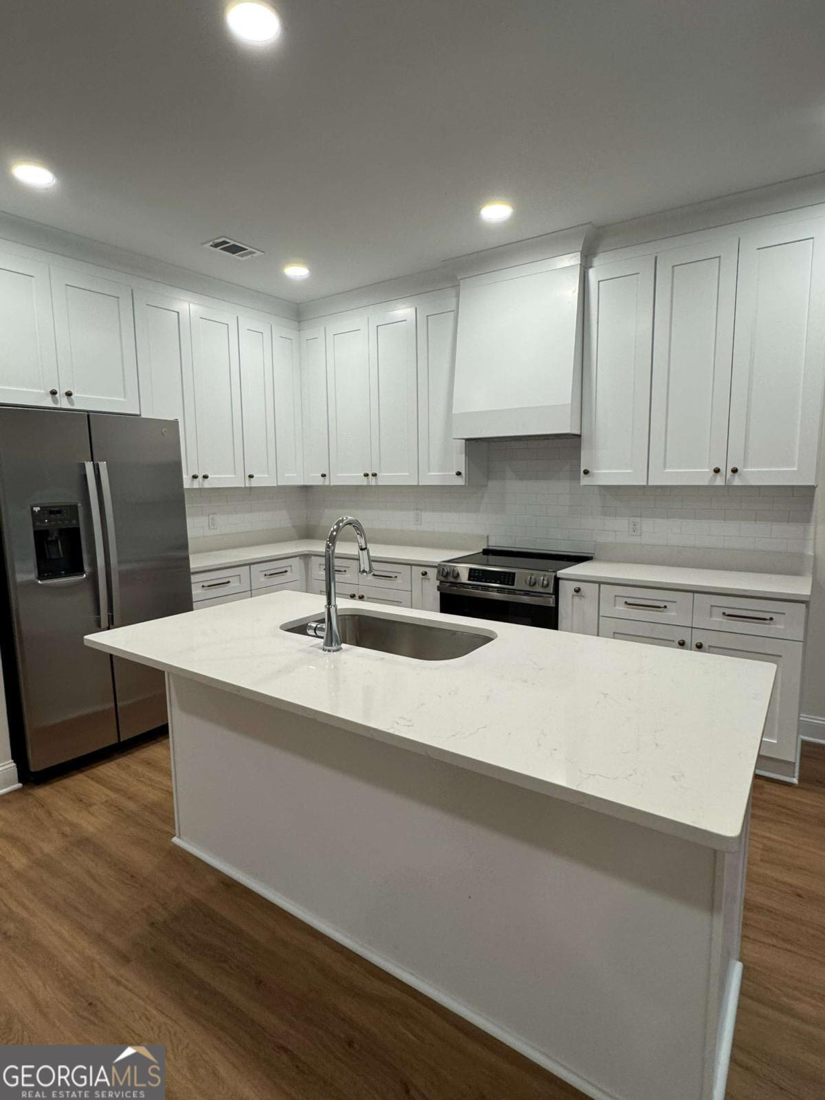 350 Rucker Lane, Unit B Statesboro, GA 30458 - Photo 5 of 20 a kitchen with stainless steel appliances granite countertop a sink a stove a refrigerator a microwave oven with white cabinets and wooden floor