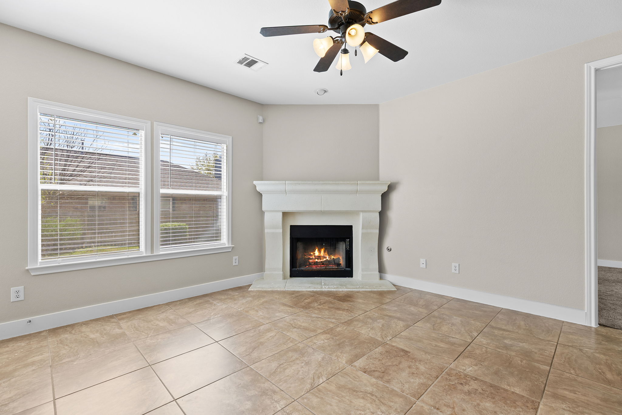3013 Hawks Swoop Trail Pflugerville, TX 78660 - Photo 23 of 38 Unfurnished living room with a ceiling fan, a lit fireplace, and light tile patterned flooring