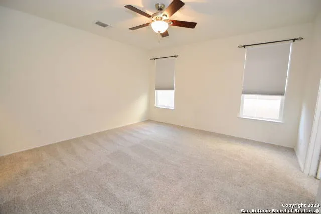 an empty room with windows and fan