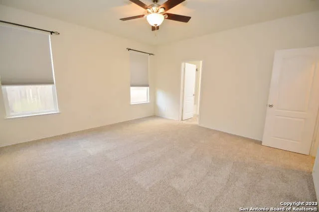 an empty room with windows and fan