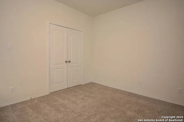 a view of an empty room with a chandelier fan