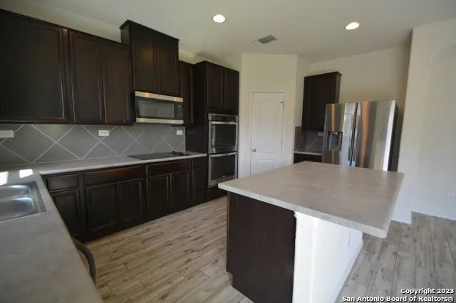 a kitchen with stainless steel appliances wooden cabinets a sink and a refrigerator