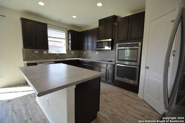 a kitchen with kitchen island a counter top space cabinets and stainless steel appliances