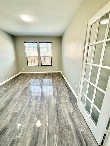 an empty room with wooden floor and windows