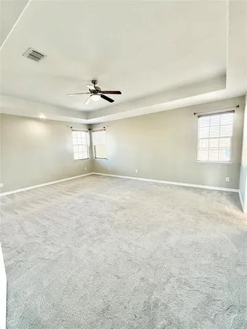 an empty room with windows and ceiling fan