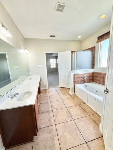 a spacious bathroom with a tub sink and mirror