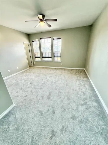 an empty room with windows and ceiling fan