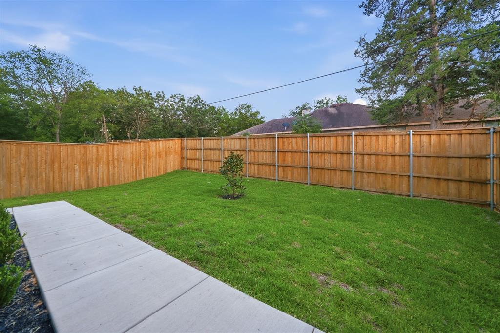 306 East 7th Street Dallas, TX 75203 - Photo 5 of 22 Expansive green lawn featuring a young tree, concrete pathway, and a perimeter wood fence with metal posts