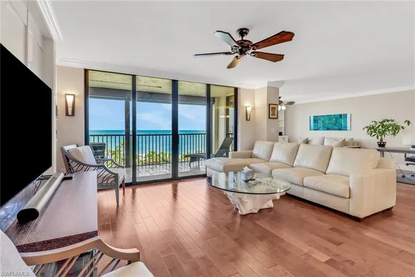 a living room with furniture floor to ceiling window and a flat screen tv