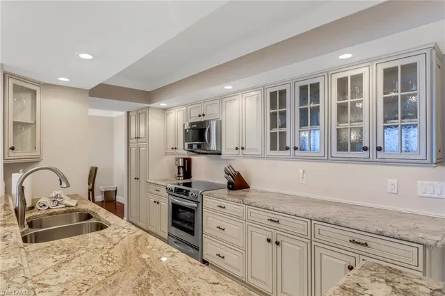 a kitchen with granite countertop a sink stainless steel appliances and cabinets