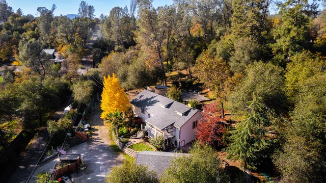 an aerial view of residential house with outdoor space and trees all around