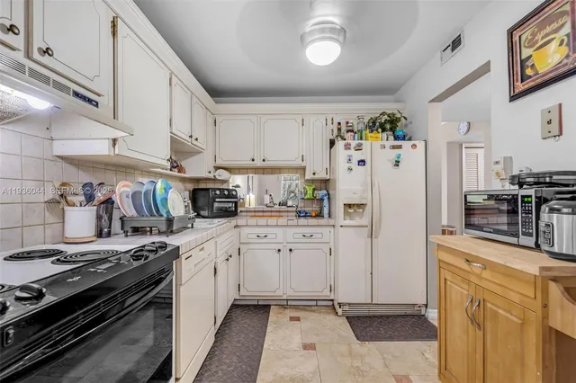a kitchen with white cabinets and appliances