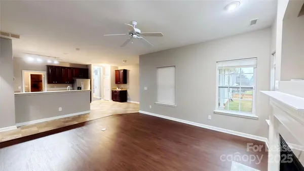 a view of a kitchen with an empty room and wooden floor and a kitchen