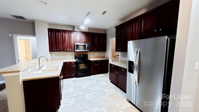 a kitchen with kitchen island granite countertop a refrigerator a sink a stove and cabinets