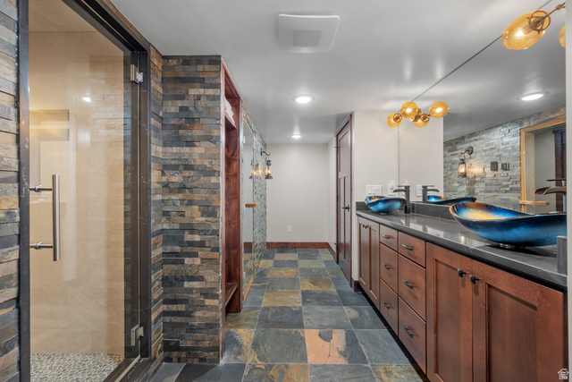 4221 Juniper Circle Alpine, UT 84004 - Photo 36 of 66 Double vanity with vessel sinks, slate tile flooring, walk-in shower with glass enclosure, stacked stone accent walls, and custom wood cabinetry