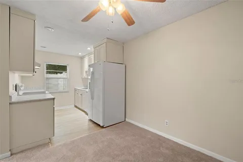 a view of a kitchen with a sink and dishwasher a refrigerator with white cabinets