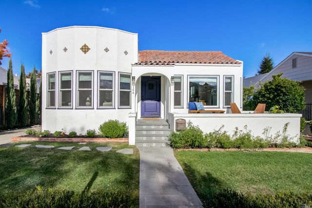 a view of a white house with a big yard and potted plants