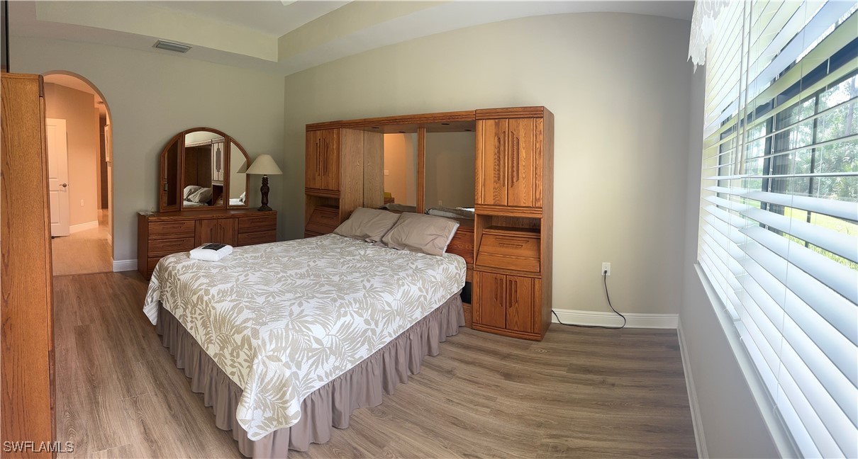 10459 Casella Way, Unit 102 Fort Myers, FL 33913 - Photo 15 of 29 a bedroom with a bed and a large window with wooden floor