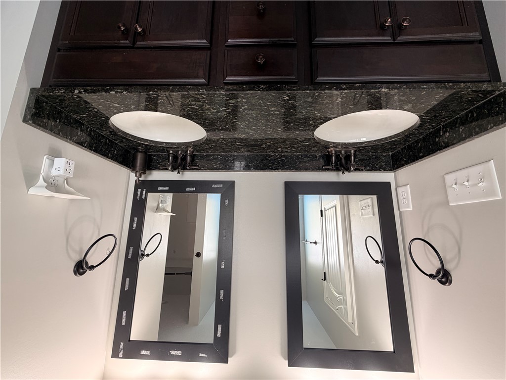 166 Pheasant Ridge Drive Anderson, SC 29626 - Photo 4 of 13 Rich dark granite countertops pair with twin sinks and matching framed mirrors below upper cabinetry.