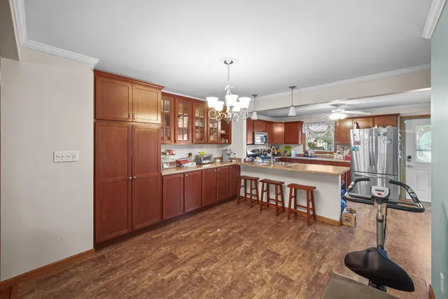 a kitchen with stainless steel appliances granite countertop a refrigerator a sink dishwasher a stove and a dining table with wooden floor