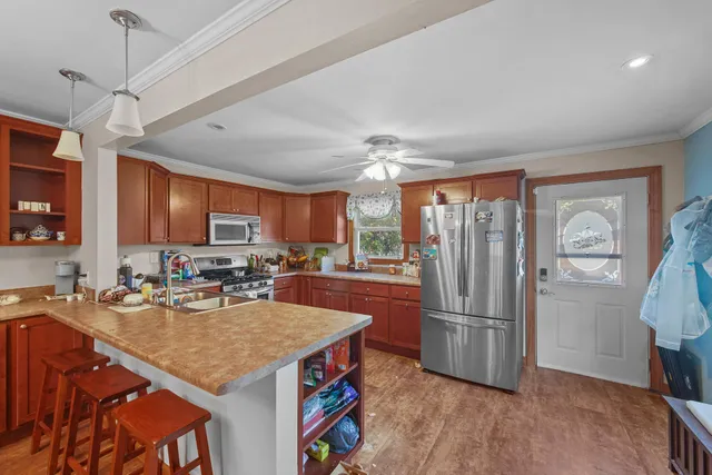 a kitchen with stainless steel appliances granite countertop a refrigerator a sink dishwasher a stove and a dining table with wooden floor