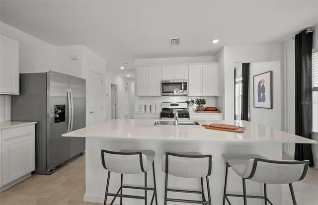 a kitchen with stainless steel appliances a table chairs refrigerator and microwave