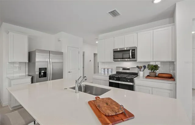 a kitchen with stainless steel appliances a stove a sink a microwave a refrigerator a counter top space and cabinets