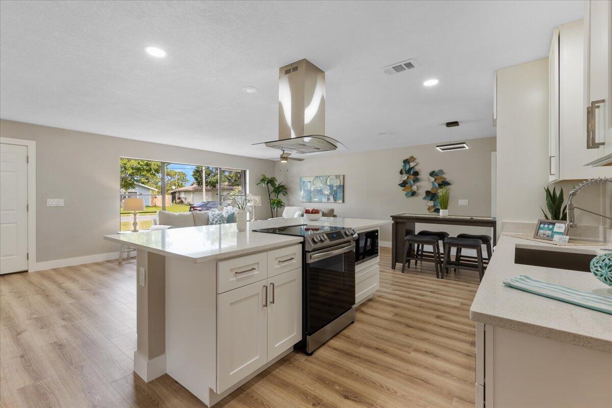 2138 Southeast Dolphin Road Port St. Lucie, FL 34952 - Photo 6 of 31 a kitchen with stainless steel appliances granite countertop a sink dishwasher stove and oven with wooden floor