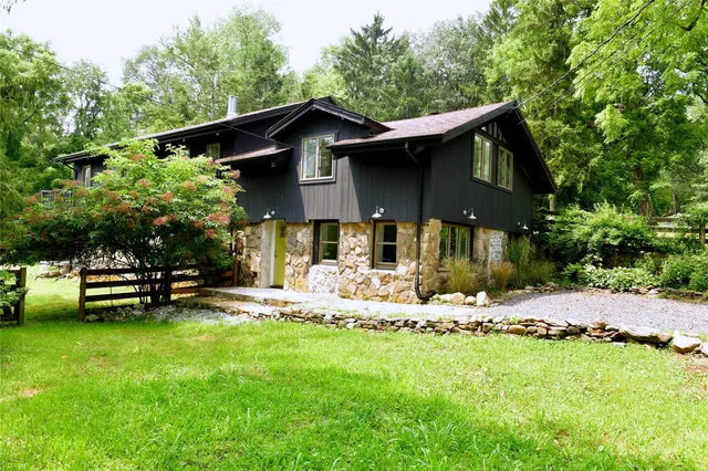 a front view of a house with a garden and trees