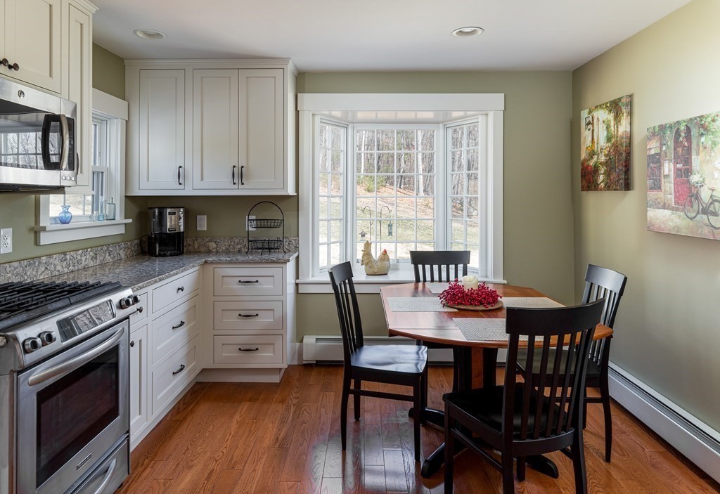 61 Ayer Road Harvard, MA 01451 - Photo 13 of 32 a kitchen with stainless steel appliances kitchen island granite countertop a stove a refrigerator a dining table and chairs with wooden floor