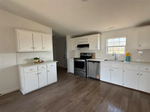 a kitchen with granite countertop white cabinets and appliances